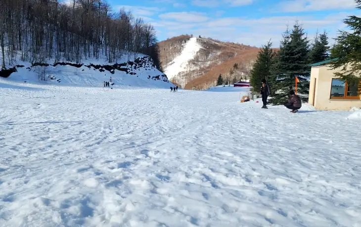 Kartepe Kayak Merkezi’nde geniş ve hafif eğimli pist alanı, arka planda ormanlık yamaçlar ve karla kaplı doğa